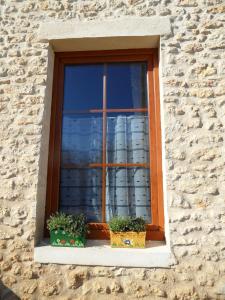 een raam met twee potplanten op een stenen muur bij Au Jardin près de l'ocean in Les Mathes