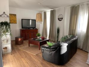 Una sala de estar con un sofá de cuero y un televisor. en Gîte Les lavandières, en Colmar