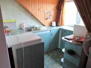 a small kitchen with blue cabinets and a sink at Panorámás apartman 4+1 in Ábrahámhegy