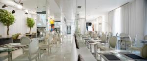 uma sala de jantar com mesas e cadeiras brancas em Dormirdcine em Madrid