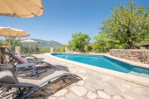 a swimming pool with lawn chairs and an umbrella at S Olivar Major in Fornalutx