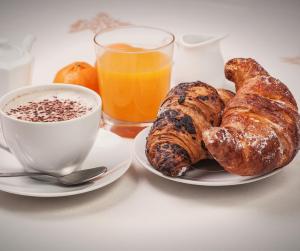a plate of pastries and a cup of coffee and a glass of orange juice at ISTAI Cagliari City Center Rooms in Cagliari