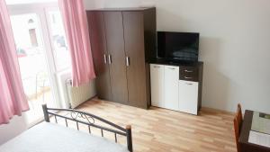 a bedroom with a bed and a cabinet with a television at Guesthouse Sermageova in Zagreb