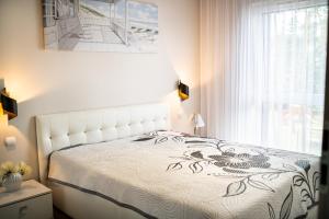 ein Schlafzimmer mit einem weißen Bett und einem Fenster in der Unterkunft Komfortowe Apartamenty Sun Seasons 24 w Pogorzelicy Blisko Morza by Noclegi Renters in Pogorzelica