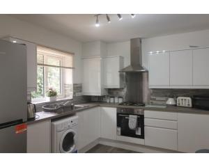 a kitchen with white cabinets and a stove top oven at Private Spacious 2 Bedroom, 2 Bathroom & 2 Parking by Srk Accommodation in Peterborough