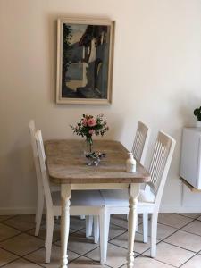 a table with three chairs and a vase of flowers on it at Allesø Gl. sognefoged gård in Odense