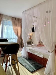 Schlafzimmer mit einem Bett mit Vorhängen und einem Tisch in der Unterkunft Beige-a-view, Sea Dreams in Sweti Wlas