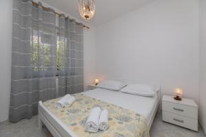 a white bedroom with a bed with towels on it at Apartments Ella in Supetar