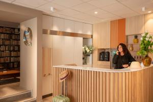 a woman standing at a counter in a library at ibis Styles Beaulieu sur Mer in Beaulieu-sur-Mer