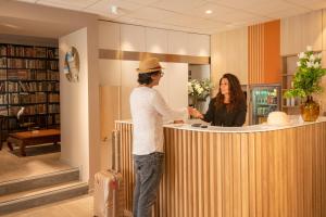 a man and a woman standing at a counter in a library at ibis Styles Beaulieu sur Mer in Beaulieu-sur-Mer
