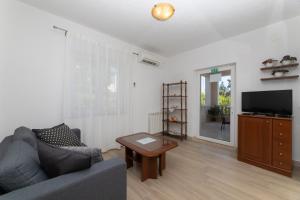 a living room with a couch and a tv and a table at Apartments Ella in Supetar