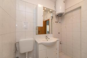 a white bathroom with a toilet and a sink at Apartments Ella in Supetar +45 photos