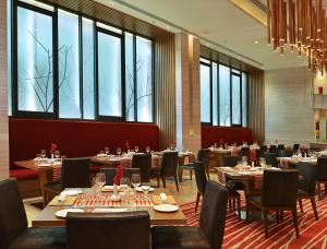 - une salle à manger avec des tables, des chaises et des fenêtres dans l'établissement Welcomhotel by ITC Hotels, Richmond Road, Bengaluru, à Bangalore