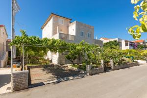 a building with a bunch of trees in front of a street at Apartments Ella in Supetar