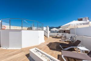 una terraza en la azotea con sillas y sombrillas en un edificio en Hotel Toboso Chaparil en Nerja