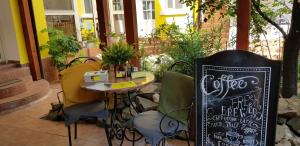 un café avec une table, des chaises et un panneau dans l'établissement Pension Casa Leone, à Timişoara