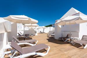 - une rangée de chaises et de parasols sur la terrasse dans l'établissement Hotel Toboso Chaparil, à Nerja