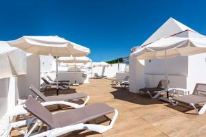 una fila di sedie e ombrelloni su un patio di Hotel Toboso Chaparil a Nerja