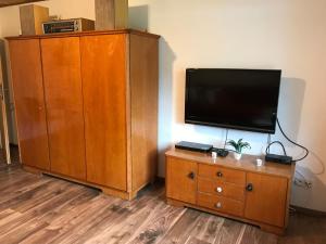 a flat screen tv sitting on top of a wooden cabinet at Helles Doppelzimmer im Untergeschoss mit Bad im Grünen nahe Potsdam in Michendorf