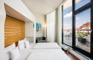a hotel room with a large bed and a large window at Art Hotel City Leipzig in Leipzig
