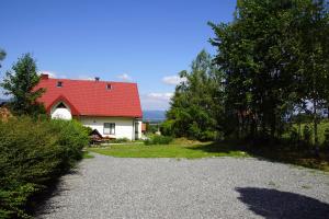 une maison avec un toit rouge et une allée en gravier dans l'établissement Dom pod Skrzycznem, à Lipowa