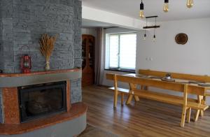 a living room with a stone fireplace and a table at Dom pod Skrzycznem in Lipowa
