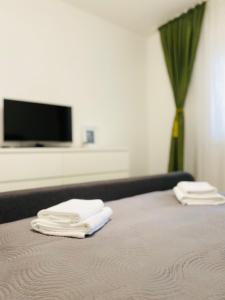 łóżko z dwoma białymi ręcznikami na górze w obiekcie AV Apartment w mieście Turda