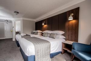 a hotel room with two beds and a blue chair at Bredbury Hall Hotel in Stockport