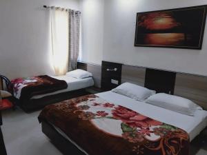 a hotel room with two beds and a picture on the wall at Hotel ShivMurti Classic in Haridwār