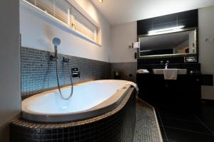a large bathroom with a tub and a sink at Maiers Kuschelhotel Loipersdorf Deluxe - ADULTS ONLY in Loipersdorf bei Fürstenfeld