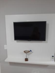 einen Flachbild-TV, der an einer weißen Wand hängt in der Unterkunft Apartamento na Praia da Enseada, 100 mt praia in São Francisco do Sul