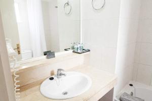 een witte badkamer met een wastafel en een spiegel bij HG Tenerife Sur in Los Cristianos