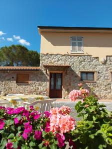 una casa de piedra con flores delante en Agriturismo Mezzo Poggio en Suvereto