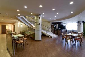 a restaurant with tables and chairs and a staircase at Voznesensky Hotel in Yekaterinburg