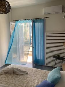 a bedroom with a bed and a window with blue curtains at Amaryllis Hotel in Rhodes Town