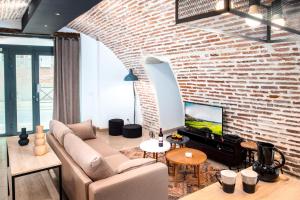 a living room with a couch and a brick wall at Le Rinaldi LOFT in Albi