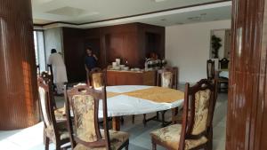 Sangam Hotel Muzaffarabad في مظفر اباد: غرفة طعام مع طاولة وكراسي وامرأة