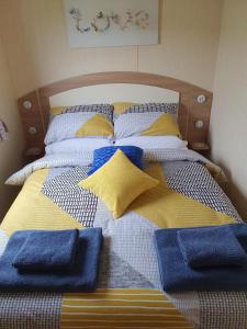 a bed with blue and yellow pillows on it at Seahawk Lodge in Whitley Bay