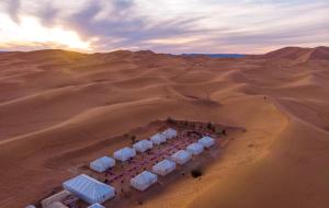 a group of white tents in the desert at Ammar Luxury Camp in Merzouga