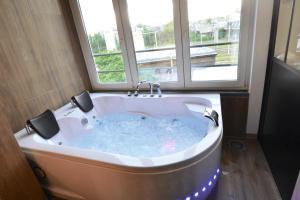 a bath tub in a bathroom with a window at Capsule Wellness - sauna - balneo - machine de sport privatif - PS5 - 2 chambres in Valenciennes