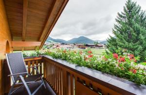 einen Stuhl auf einem Balkon mit Blumen und einem Baum in der Unterkunft Ferienwohnungen Beim Hausbacher in Reit im Winkl