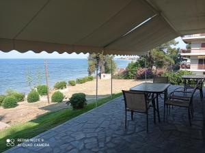 a patio with tables and chairs and the ocean at Sunset Apartment in Epanomi