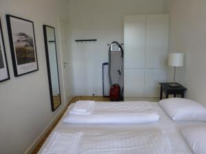 um quarto com uma cama branca e uma mala vermelha em Australiensvej em Copenhague