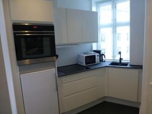 uma cozinha com armários brancos e um micro-ondas em Australiensvej em Copenhague