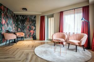 a living room with pink chairs and a table at Hotel Greenside Texel in De Koog