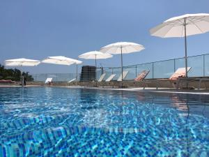 a swimming pool with chairs and umbrellas on a building at Comfort studio with sea view and swimming pool in Becici