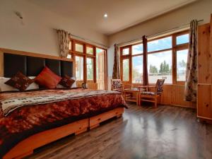 a bedroom with a bed and a desk and windows at Glacier View Guest House in Leh