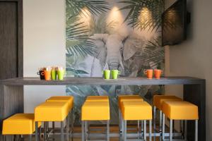 a bar with yellow stools and a mural of an elephant at ibis Styles Beaulieu sur Mer in Beaulieu-sur-Mer