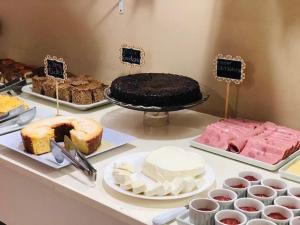 una tavola ricoperta con diversi tipi di torte e prodotti da forno di Hotel Centenário a Juiz de Fora