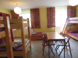 a room with bunk beds and a table and a desk at Hostel Waldhaus am Ferienpark-Mehrbett-Gruppenzimmer mit Waschbecken in Mirow +16 photos